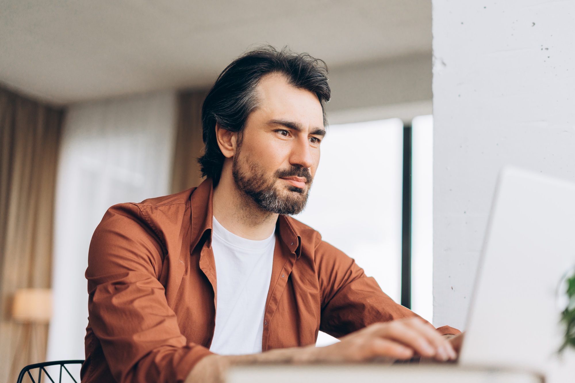 Focused freelancer working remotely on laptop at home