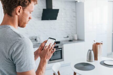 Rear view of adult man that is indoors controlling smart home technology